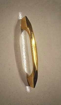 Image (15) Sleek gold-finished pull handle with a sculpted, tapered design, offering a modern and luxurious touch to doors or furniture.
