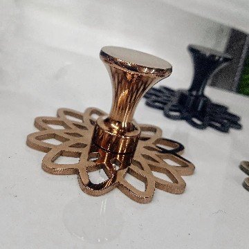 Image (22) Decorative rose gold-finished cabinet knob with a flared top and intricate floral-patterned base plate, designed for luxury furniture.