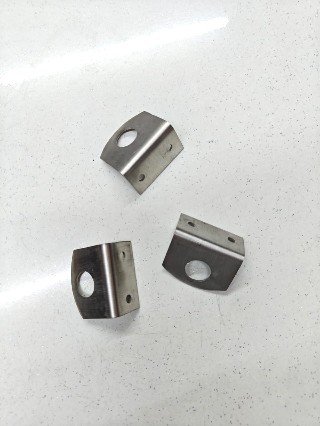 Image (23) small stainless steel corner brackets with a large central hole and two smaller screw holes for mounting, placed on a white speckled surface