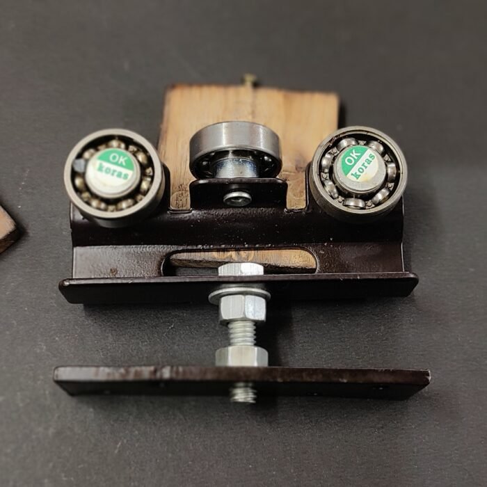 1 (6) Heavy-duty sliding gate roller assembly with three ball-bearing wheels mounted on a black metal base and wooden support blocks