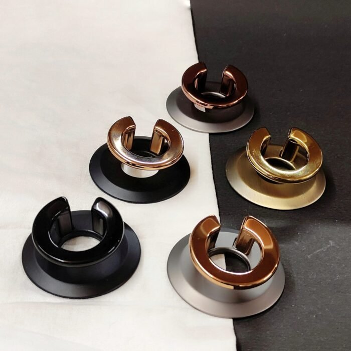 Set of five metallic door stoppers in different finishes – black, bronze, copper, gold, and chrome – displayed on a fabric and dark background.