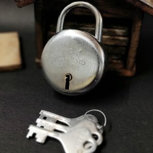 Silver heavy-duty padlock with engraved design, shown with two matching keys on a wooden dark background.