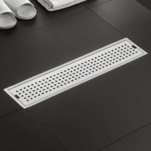 Sleek linear stainless steel drain cover with square grid holes on a white background.